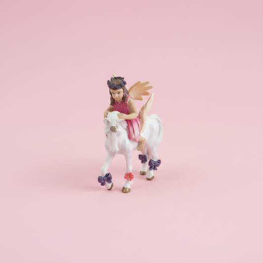 Fairy riding unicorn figurine studio photo pink background