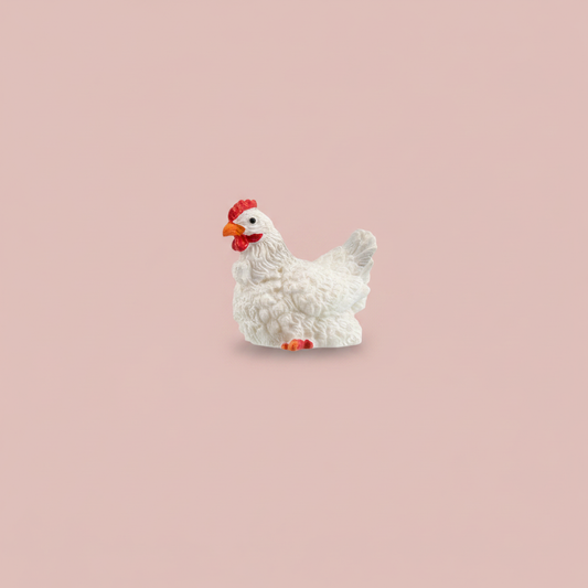 Chicken figurine photographed on a solid blush pink studio background with soft, even lighting
