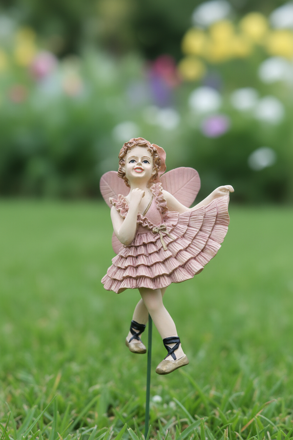 Fairy ballerina figurine in dusty pink tutu planted in garden grass