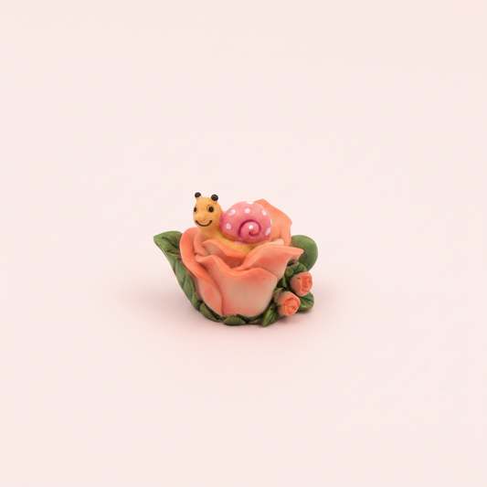 Flower with snail on pale pink background